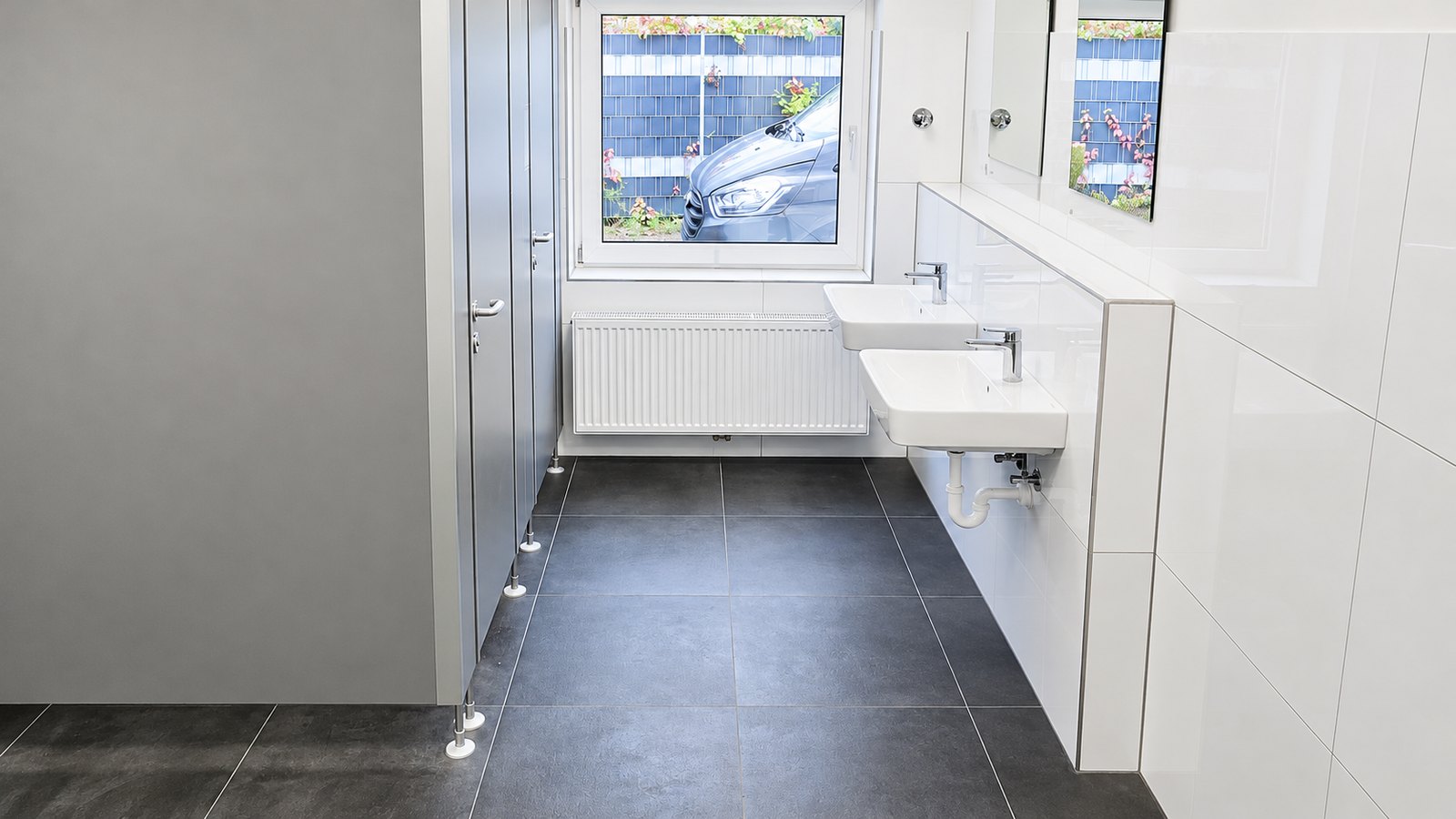 Fertig sanierter Sanitärraum mit großformatigen Bodenfliesen – Bauleistungen GD